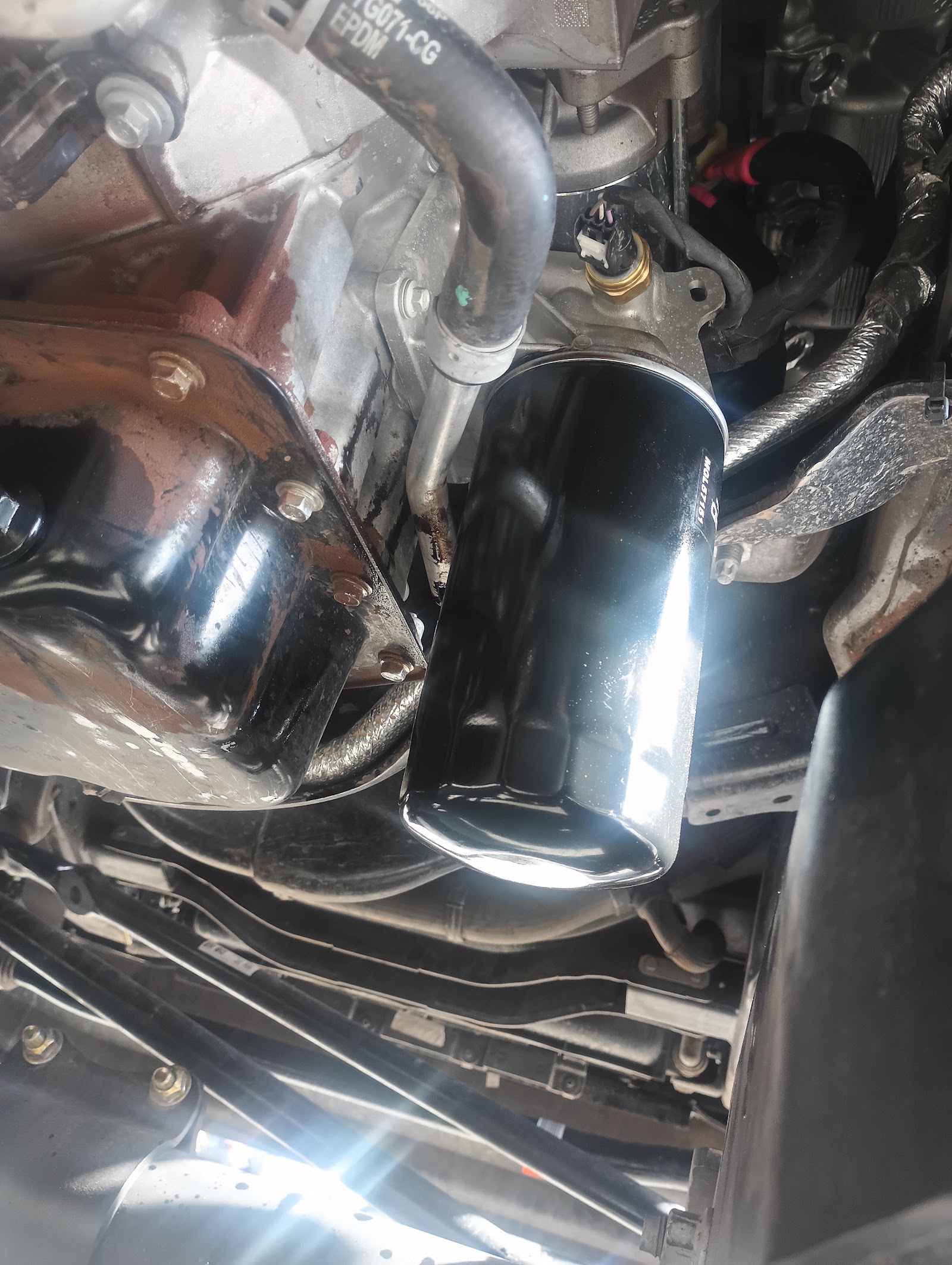 Close-up of a new black oil filter installed on a vehicle's engine underside